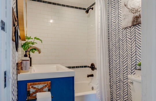 bathroom, tile shower surround, shower/tub, toilet, sink, luxury vinyl flooring