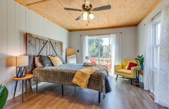 bedroom, luxury vinyl flooring, sliding door to back deck, beadboard ceiling, windows, ceiling fan