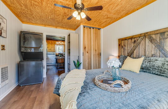 bedroom, beadboard ceiling, luxury vinyl flooring, closet, stacked washer/dryer hookup, door to kitchen