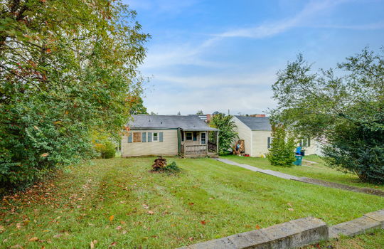 back of home, back yard, vinyl siding, bungalow, missing window, covered back porch, fixer upper, trees, neighboring home, sidewalk