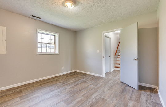 lower level bedroom, laminate flooring, door to hallway, stairs to main level