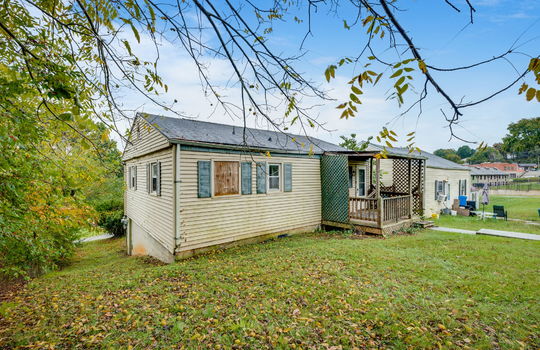 back of home, back yard, vinyl siding, bungalow, missing window, covered back porch, fixer upper, trees, neighboring home, sidewalk