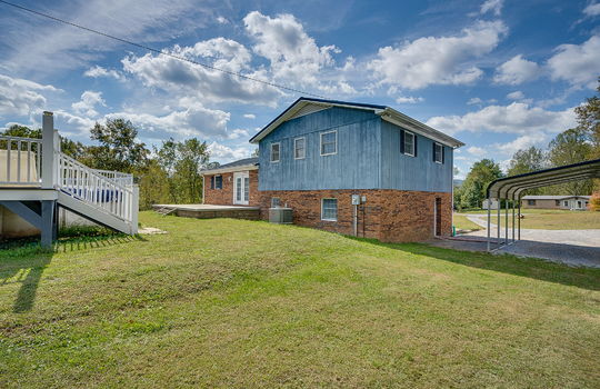 back side view of home, wood siding, brick, carport, gravel driveway, back yard, above ground pool, back patio