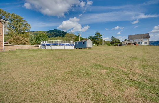 back yard, gated/fenced above ground pool, storage shed, neighboring home, trees, mountain view, back patio