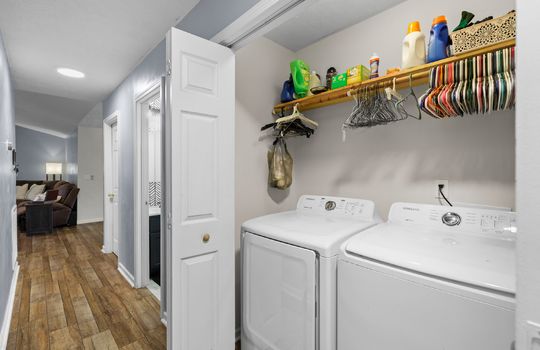 laundry closet, washer/dryer hookups, shelving, hallway, laminate flooring