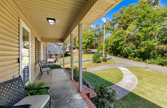 covered front porch, concrete porch, front door, vinyl siding, brick steps, sidewalk, front yard, driveway