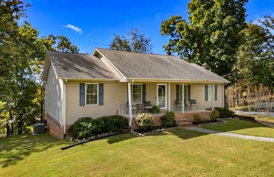 ranch style home, vinyl siding, covered front porch, front yard, landscaping, front door, storm door, shingle roof, heat pump, trees
