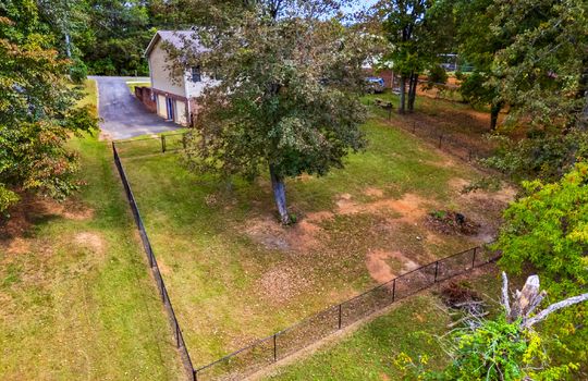 aerial photo toward back of home, fencing, back yard, driveway, two car drive under garage