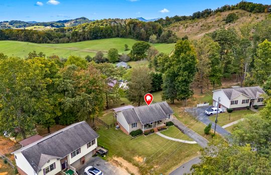 aerial photo, property marker, neighboring homes, front yard, sidewalk, driveway, covered front porch, back deck, fenced back yard, mountains, trees
