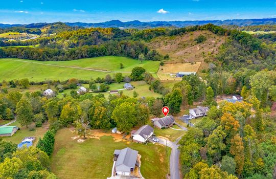 aerial photo, property marker, neighboring homes, front yard, sidewalk, driveway, covered front porch, back deck, fenced back yard, mountains, trees