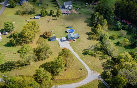 Aerial photo of property, driveway, yard, front yard, back yard, trees, above ground pool, neighboring homes