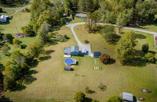 Aerial photo of property, driveway, yard, front yard, back yard, trees, above ground pool, neighboring homes