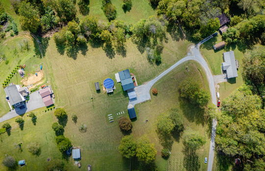 Aerial photo of property, driveway, yard, front yard, back yard, trees, above ground pool, neighboring homes