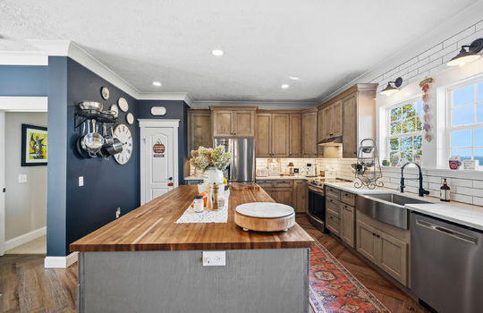 kitchen, large kitchen island with butcher block countertop, stainless appliances, refrigerator, oven/range, sink, dishwasher, cabinets, quartz countertops, luxury cabinets, tile backsplash