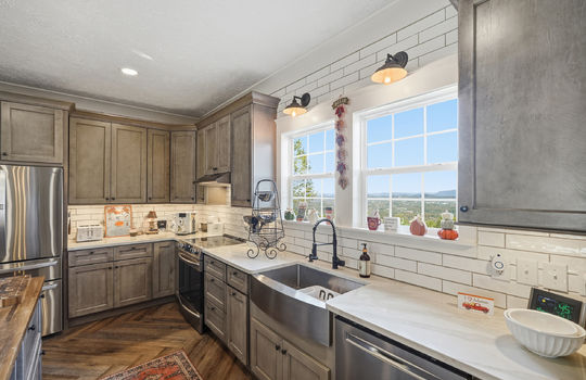 kitchen, high-end cabinetry, tile backsplash, window with mountain views, sink, stainless steel appliances, refrigerator, oven, dishwasher