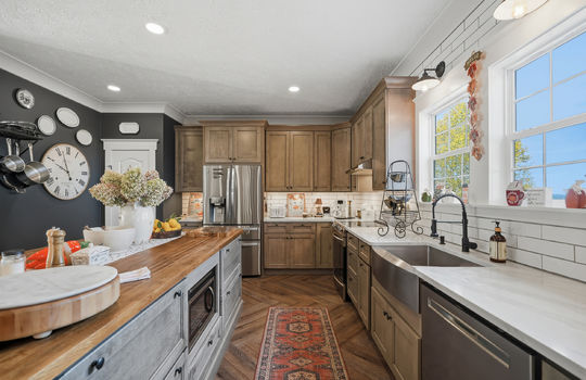 kitchen, 8 foot kitchen island, butcher block countertop, quartz countertops, high-end cabinetry, tile backsplash, window above sink, sink, refrigerator, oven/range, dishwasher, luxury vinyl flooring