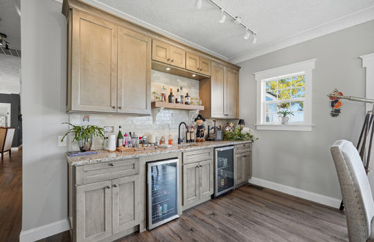 family room, wet bar, sink, mini fridge, wine cooler, high end cabinetry, track lighting, window, luxury vinyl flooring