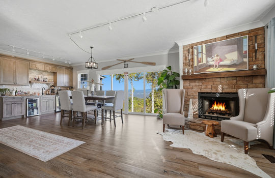 family room, fireplace, large windows with mountain views, wet bar, tile backsplash, wine cooler, mini fridge, sink, luxury vinyl flooring