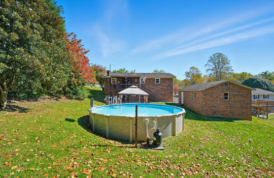 back yard, detached garage, above ground swimming pool, fencing, trees, back of home, back deck back patio, seating area