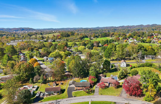 aerial view of home, driveway, brick ranch, detached garage, neighboring homes, mountain views