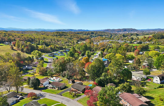 aerial view of home, driveway, brick ranch, detached garage, neighboring homes, mountain views