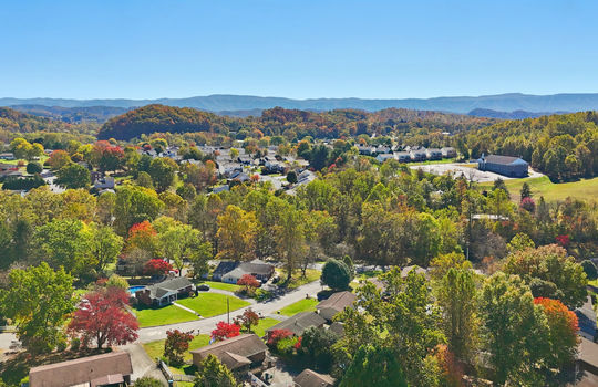 aerial view of home, driveway, brick ranch, detached garage, neighboring homes, mountain views