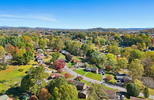 aerial view of home, driveway, brick ranch, detached garage, neighboring homes, mountain views