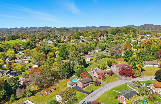 aerial view of home, driveway, brick ranch, detached garage, neighboring homes, mountain views