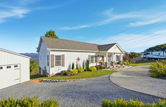 modular home, detached garage, driveway, covered front porch, landscaping, vinyl siding, RV parking, mountain views