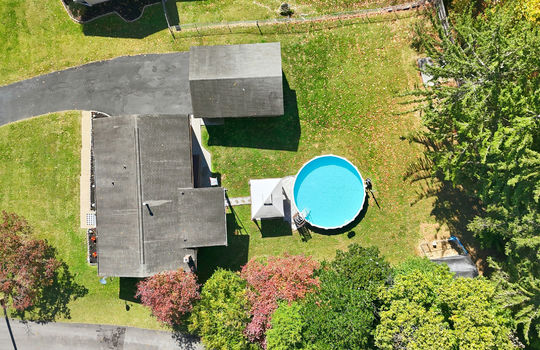 aerial overhead view of home, driveway, roof, garage roof, back deck, above ground pool, fencing, back yard, front yard, sidewalk