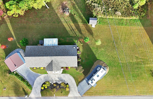 overhead aerial view of home, roof, RV parking area, detached garage, shed, driveway, front yard, back yard, landscaping