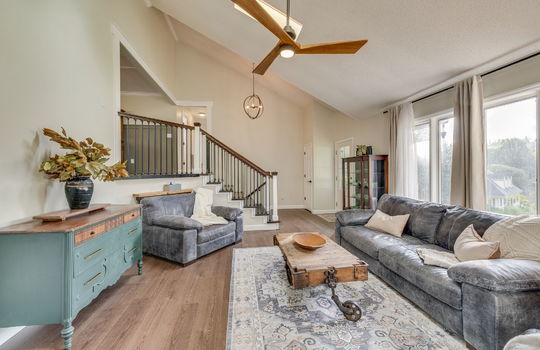 living room, luxury vinyl flooring, front door, windows, ceiling fan, stairs to next level, skylight