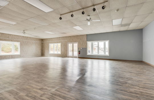 interior of commercial space toward front entry doors, commercial building for lease, vinyl flooring, ceiling tiles, fluorescent lighting