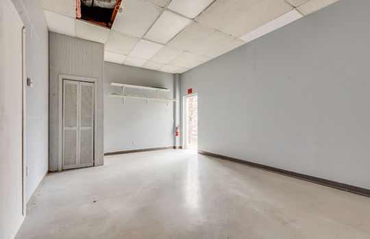 Private office space or employee break room, tile flooring, Ceiling tiles, fluorescent lighting, back entry/employee exit door, storage shelves