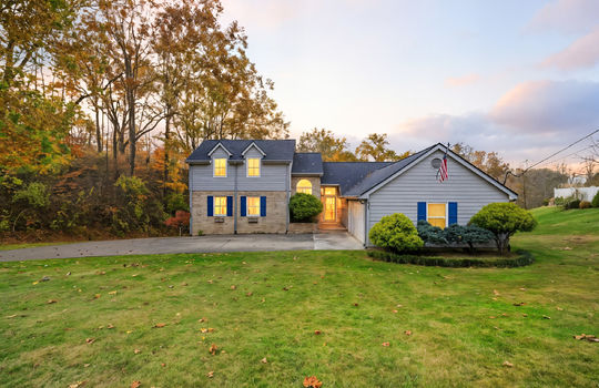 Twilight photo, traditional style home, front yard, front driveway, garage, landscaping, trees, wood siding, brick, front door