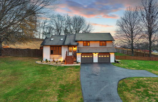 twilight photo, front yard, driveway, two car garage, contemporary style home, brick & wood siding exterior, fencing , trees, landscaping