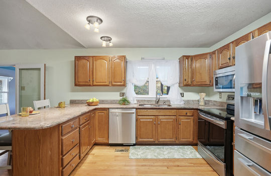 kitchen, granite countertops, cabinets, stainless steel appliances, dishwasher, sink, stove, built in microwave, refrigerator, window above sink, hardwood flooring, bar seating