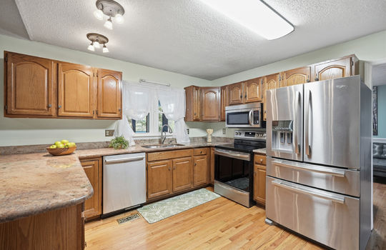 kitchen, granite countertops, cabinets, stainless steel appliances, dishwasher, sink, stove, built in microwave, refrigerator, window above sink, hardwood flooring, bar seating