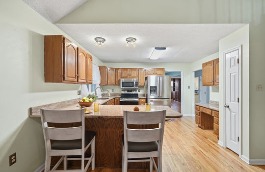 kitchen, granite countertops, cabinets, stainless steel appliances, dishwasher, sink, stove, built in microwave, refrigerator, window above sink, hardwood flooring, bar seating, pantry