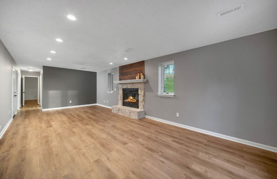 den, luxury vinyl flooring, fireplace, painted stone fireplace, windows