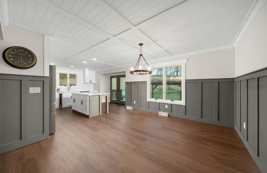 dining space, board and batten wainscoting, chandelier, kitchen island sink, door to back yard