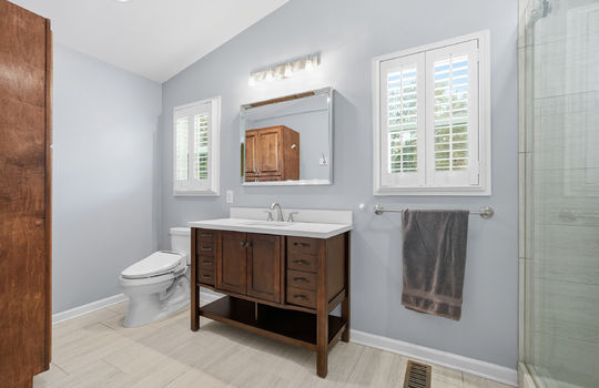 ensuite bathroom, toilet, sink, tile shower, glass shower door, indows, tile flooring