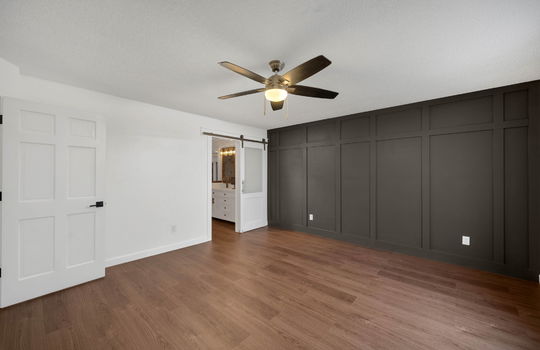 primary bedroom, board and batten feature wall, ceiling fan, luxury vinyl flooring, barn door, primary ensuite, ceiling fan