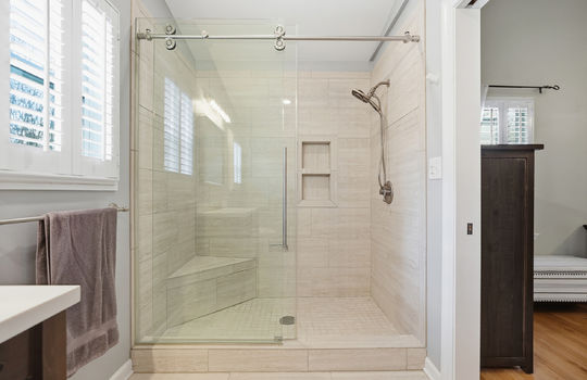 ensuite bath tile shower, tile shower, glass sliding shower door, windows, tile flooring
