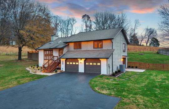 twilight photo, yard, driveway, two car garage, landscaping, contemporary home, wood siding, brick exterior, fencing, stairs to front door, front door