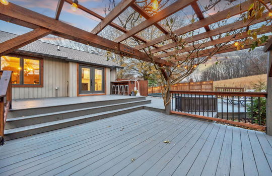 pergola, back deck, bar seating, pool, fencing, view of field, back of home, wood siding