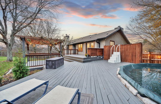 back deck, swimming pool, lounge area, bar seating, pergola, landscaping, back of home, wood siding, fencing