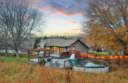 back of home, fencing, landscaping, above ground pool, back deck, pergola, wood siding