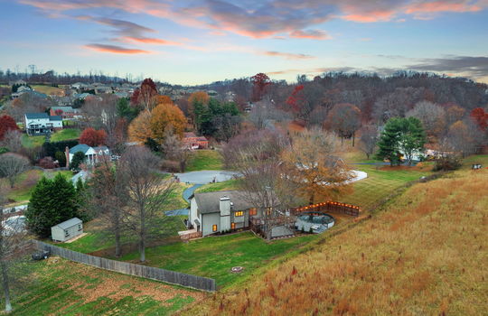 aerial view of back of home, neighboring homes, fencing, back yard, back deck, trees, landscaping