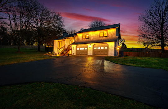twilight photo, contemporary home, garage doors, wood siding, driveway, fencing, stairs to front door